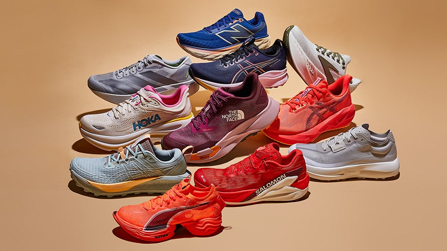 A collection of ten colorful running shoes from various brands arranged on a beige surface. They are displayed in a dynamic, overlapping fashion.