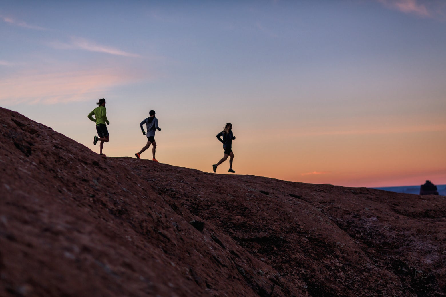 Three people trail running during sunset