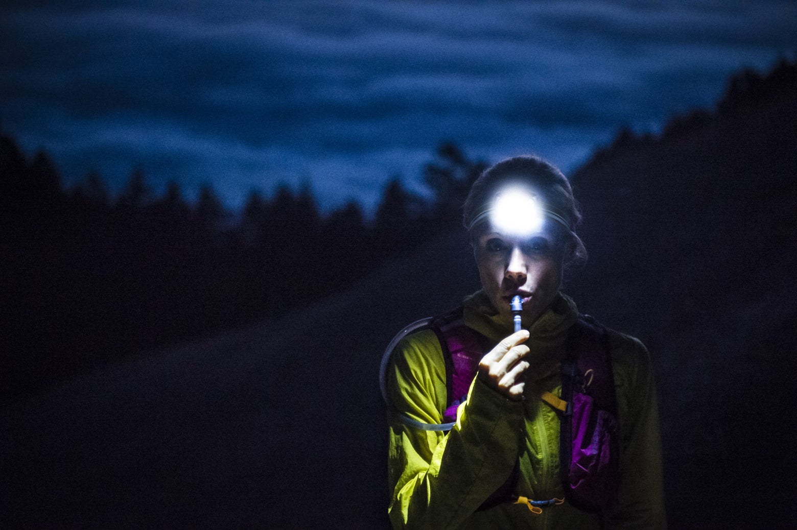 Female trail runner wearing a headlamp and hydration vest 