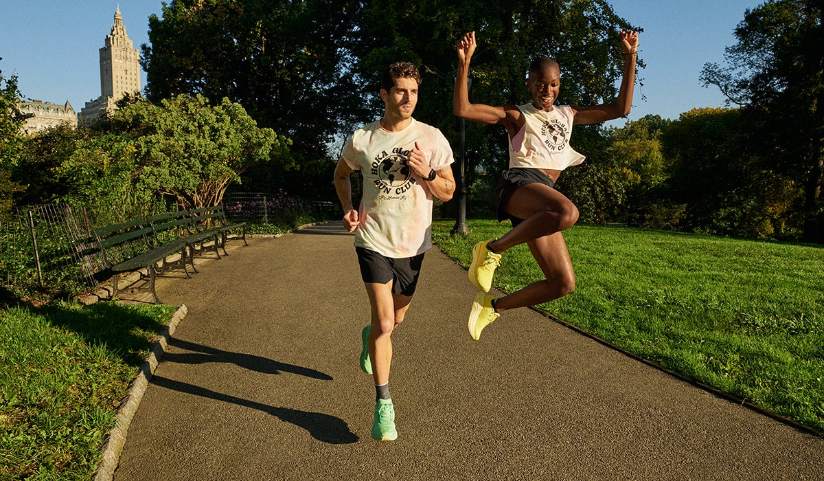 Two people running in a park wearing plated running shoes