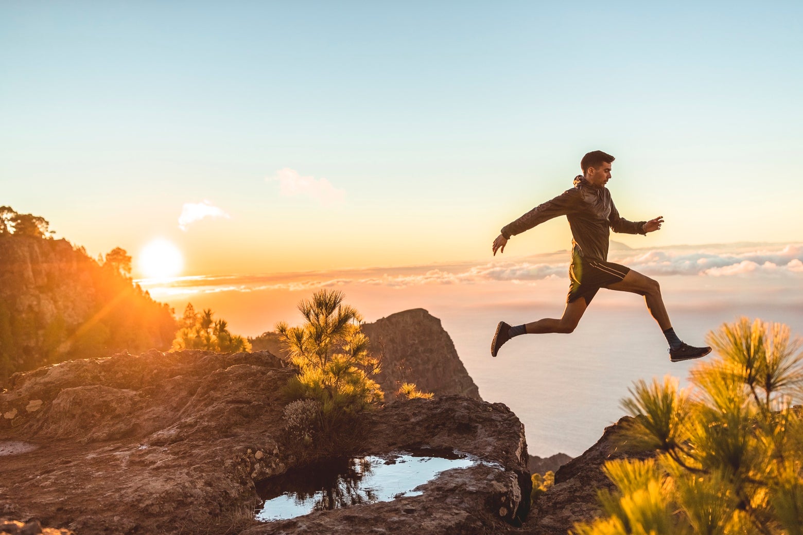 Trail runner jumping over a puddle of water 