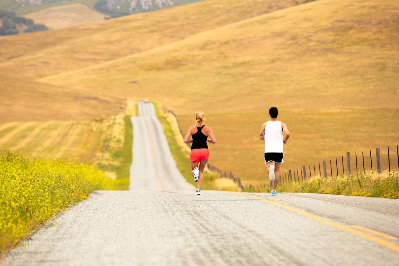 A male and female runner running on an open road