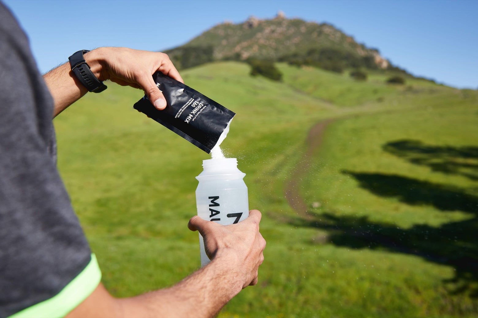 Close up shot of a man pouring a Maurten Drink Mix outdoors