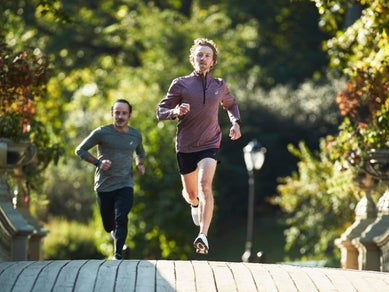 Two men running on a boardwalk wearing half zip and long sleeve ASICSshirts