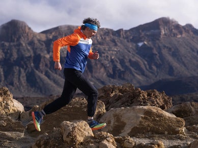 Man trail running wearing an orange and navy Brooks jacket