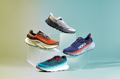 Four trail running shoes stacked on top of boxes, featuring New Balance, Salomon and HOKAs