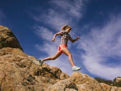 Woman trail running wearing rabbits High Country plaid shirt and rabbit shorts