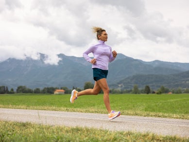 Woman wearing Brooks shorts and half zip running outdoors