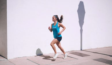 Woman running on the sidewalk wearing headband and tank