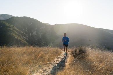 Man running in dry field in blue jacket