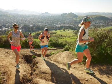Group of people in athletic clothes running up a mountain trail 