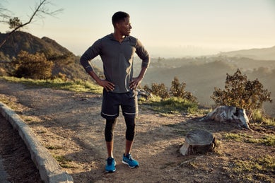 Male runner resting hands on hips