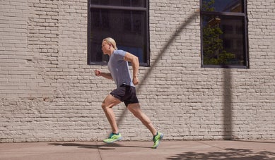 Man running on the sidwalk next to a brick building