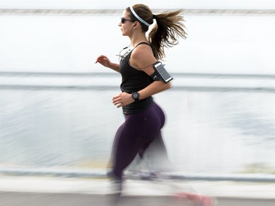 Woman running with sunglasses and a phone arm band