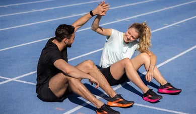Man and woman sitting on the track high fiving each other