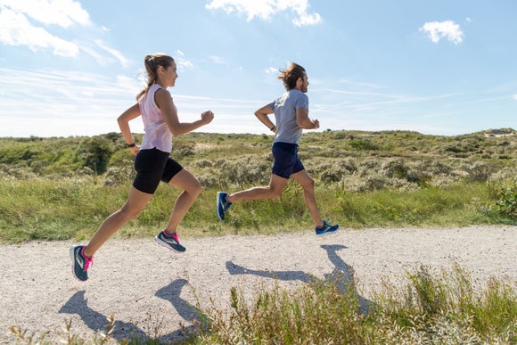 A man and woman running outdoors on a sunny day.