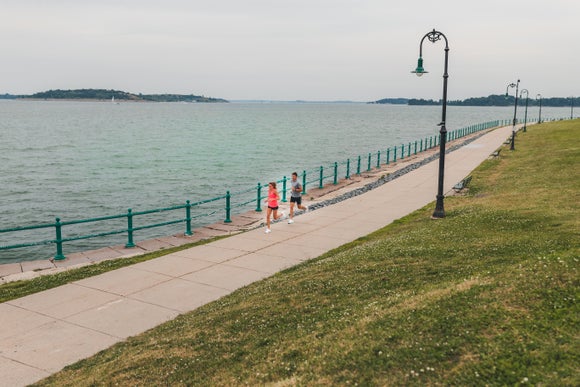 Man and Woman running along a path next to a body of water.