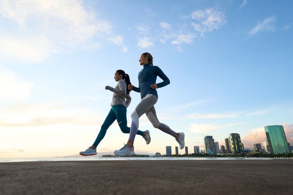 Two woman running by the beach wearing Hokas