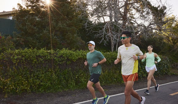 Group of runners running in a neighborhood with the sun shining