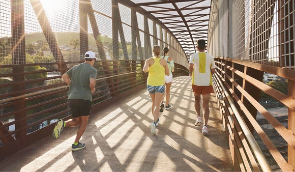 Group of runners running across bridge on a sunny day