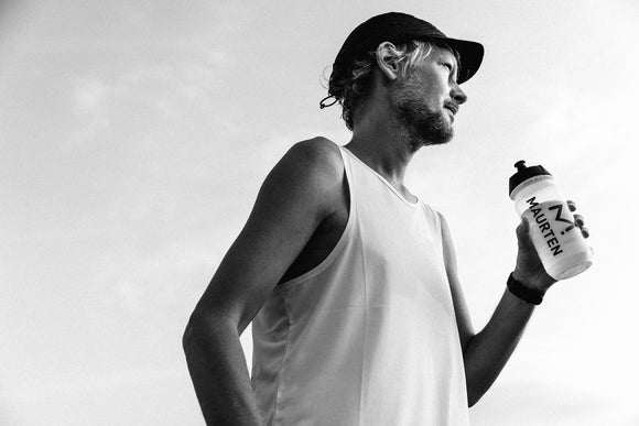 Black and white photo of a male holding a Maurten drink mix bottle