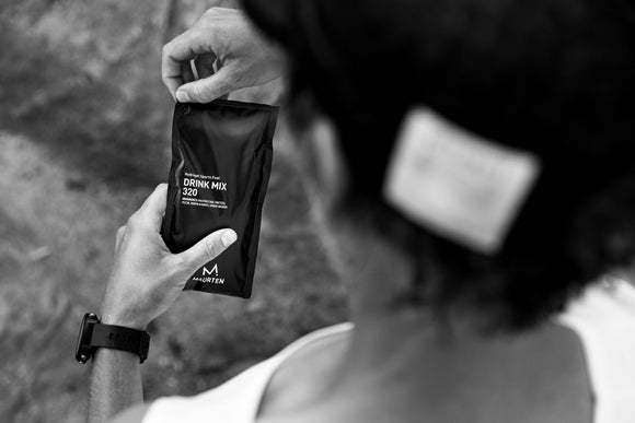 Black and white photo of a man holding a Maurten drink mix