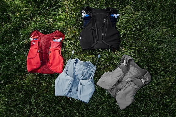 Four Salomon hydration packs laid on top of grass