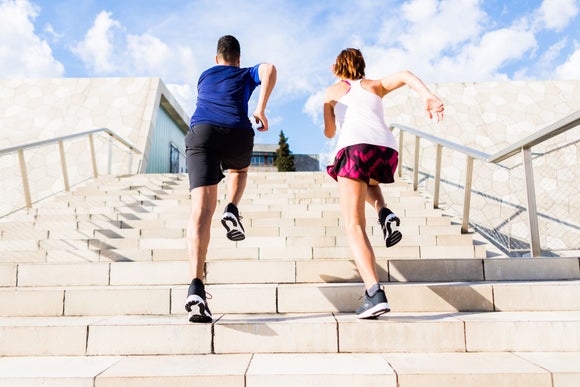Man and woman outdoors running up the stairs