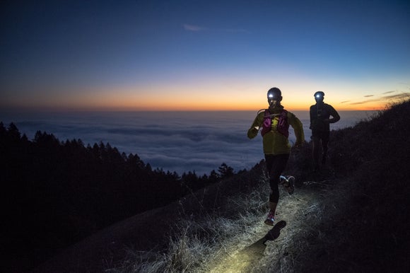 female runner wearing a headlamp, gloves, and beanie during a cold weather run