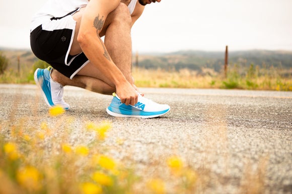 A runner lacing up his HOKA Carbon X running shoes