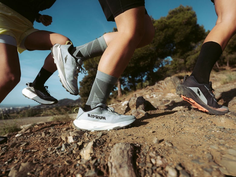 Three athletes running on a trail wearing the Kipsummit shoe. 