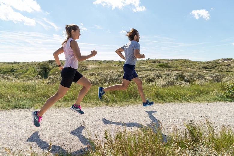 A man and woman running outdoors on a sunny day.