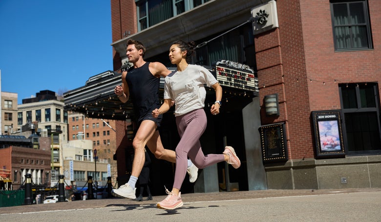 two runners running on an urban street wearing HOKA Clifton shoes