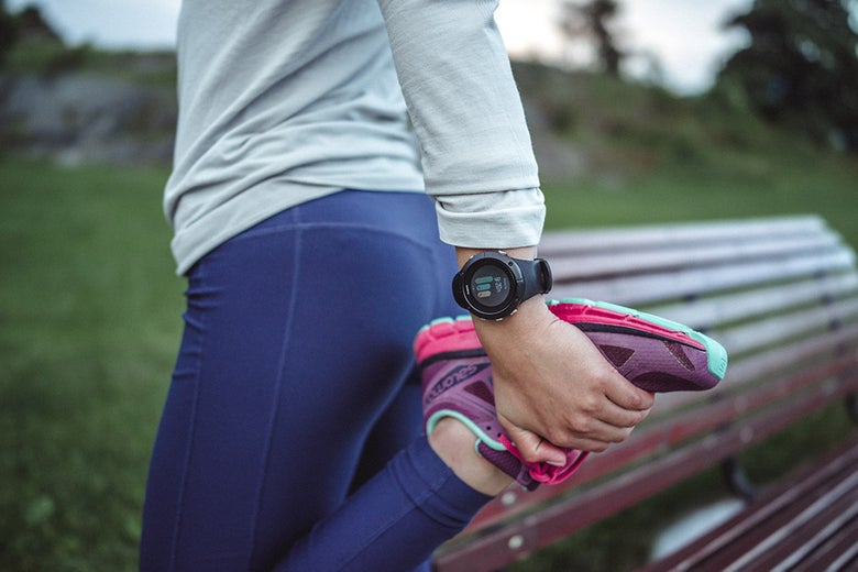 Woman stretching grassy area with watch