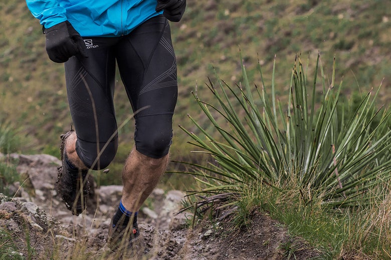 Runner with black shoes running through mud