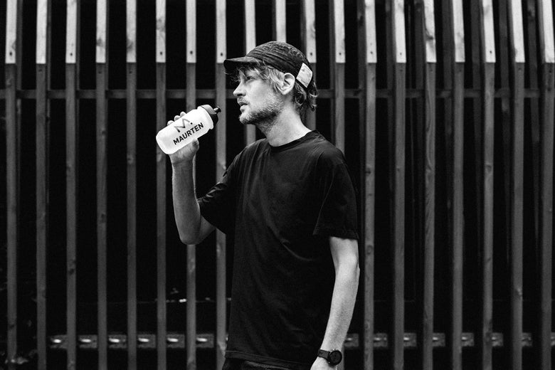 male runner drinking from maurten bottle