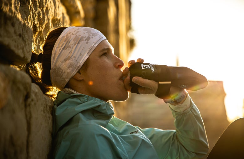 Woman wearing a headband and drinking water from a flask
