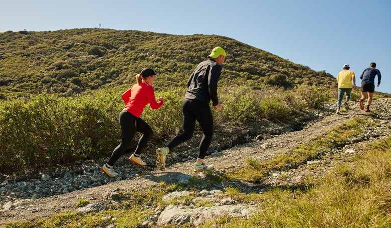 Running Warehouse employees running uphill on a trail in SLO testing out different models of trail shoes 
