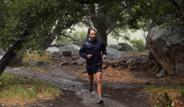 Runner in trees running on muddy trail