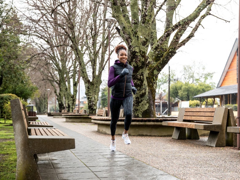 female runner wearing a vest running in wet weather
