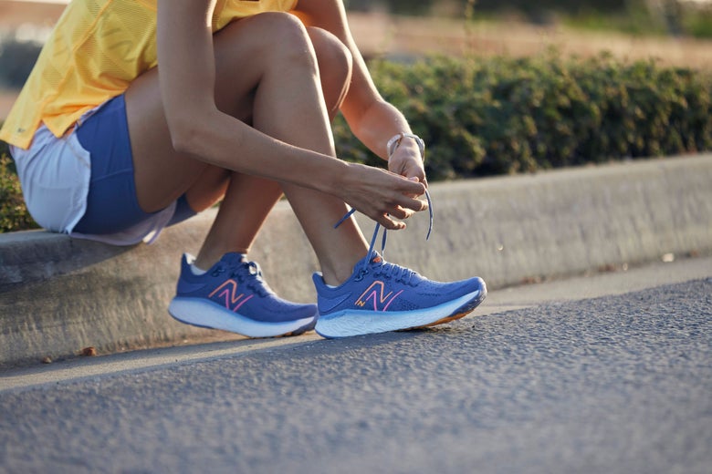 Runner seated on curb tying shoes