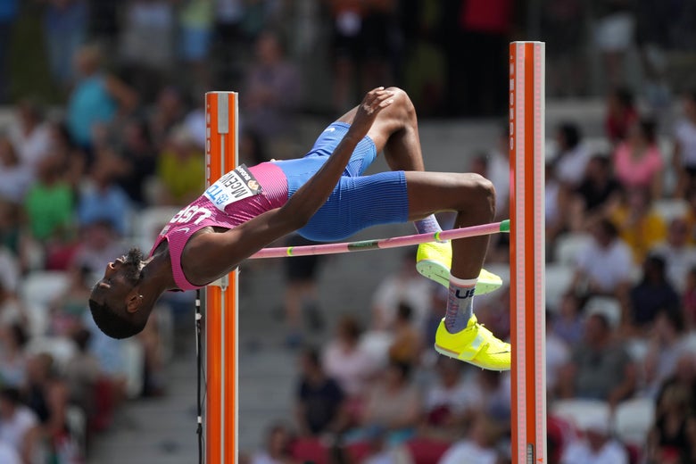 High jumper in USA kit, at apex clearing the bar