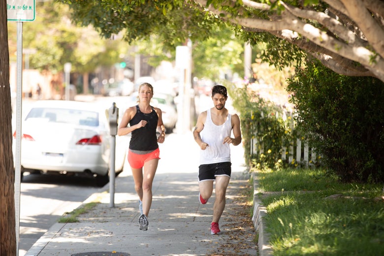 Two runners headed towards camera on sidewalk