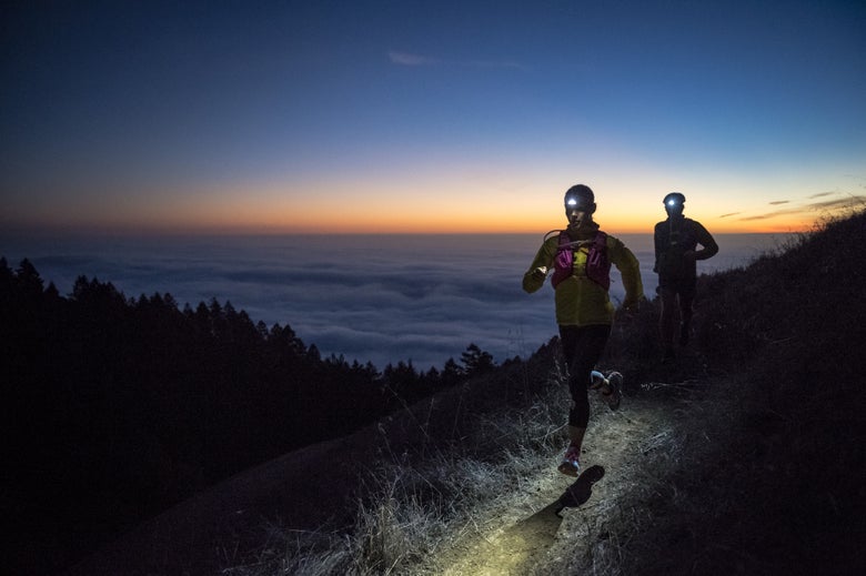 Two trail runners wearing headlamps  