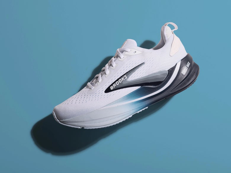 side view of the Brooks Ghost Max in white/blue, against a blue studio background
