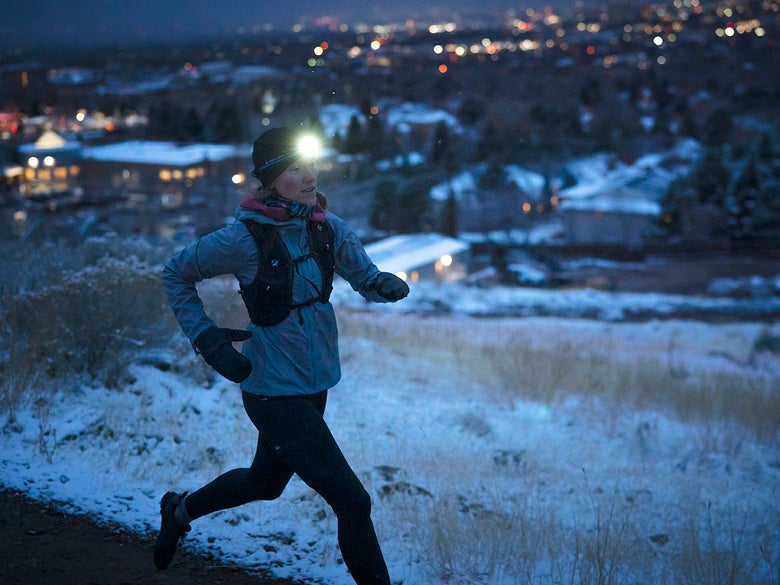 Female runner at night with headlamp on.