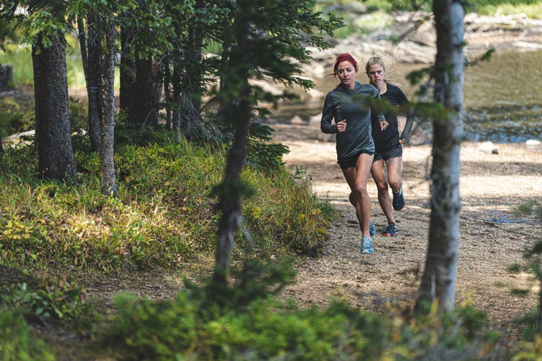 Two women running on a dirt path.