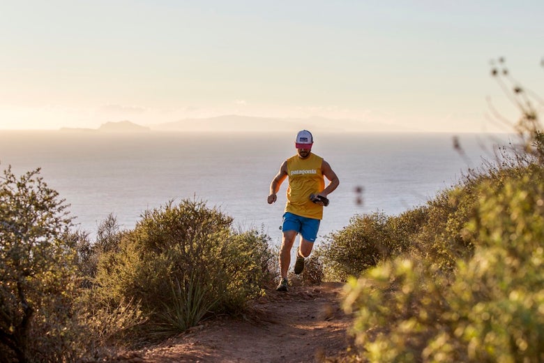 trail runner with gear running in the mountains near the ocean