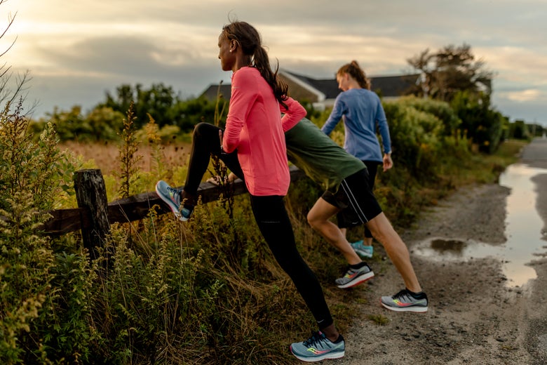 Runners stretching along a fence