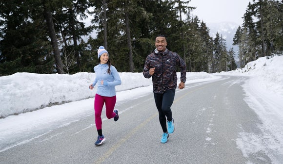 man and woman running outside in the wintertime wearing jackets and tights